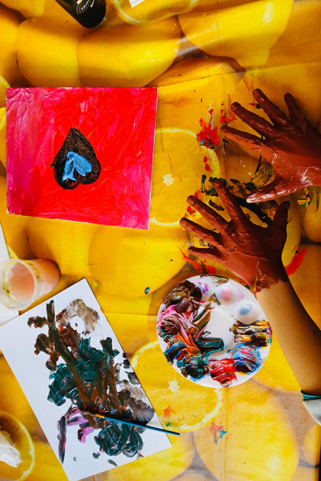 Kinderhände mit Malfarbe auf gelbem Untergrund