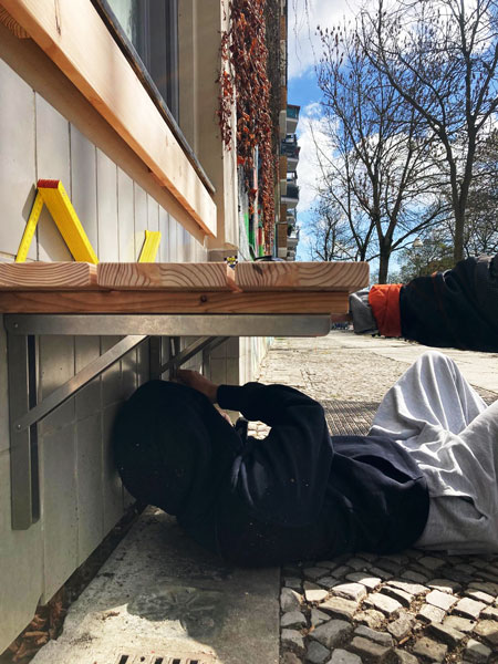 4 Personen beim Aufbau eines Holzdachs übereiner Holzterasse im Hinterhof