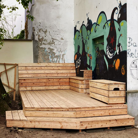 Selbstgebaute Holzterrasse mit Sitzbänken im Hinterhof