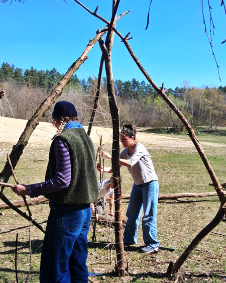 2 Erzieher*innen bauen aus Ästen ein Tipi