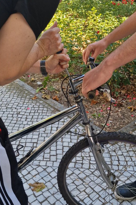 Mitarbeitender aus dem Betreuten Jugendwohnen schraubt am Fahrradsessel