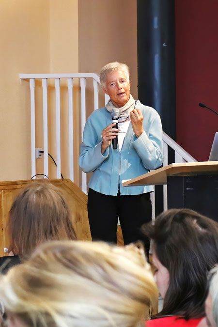 Prof. Silke Gahleitner von der der ASH Berlin mit Mikrofon in der Hand bei ihrem Vortrag zu den Wirkfaktoren der Jugendhilfe